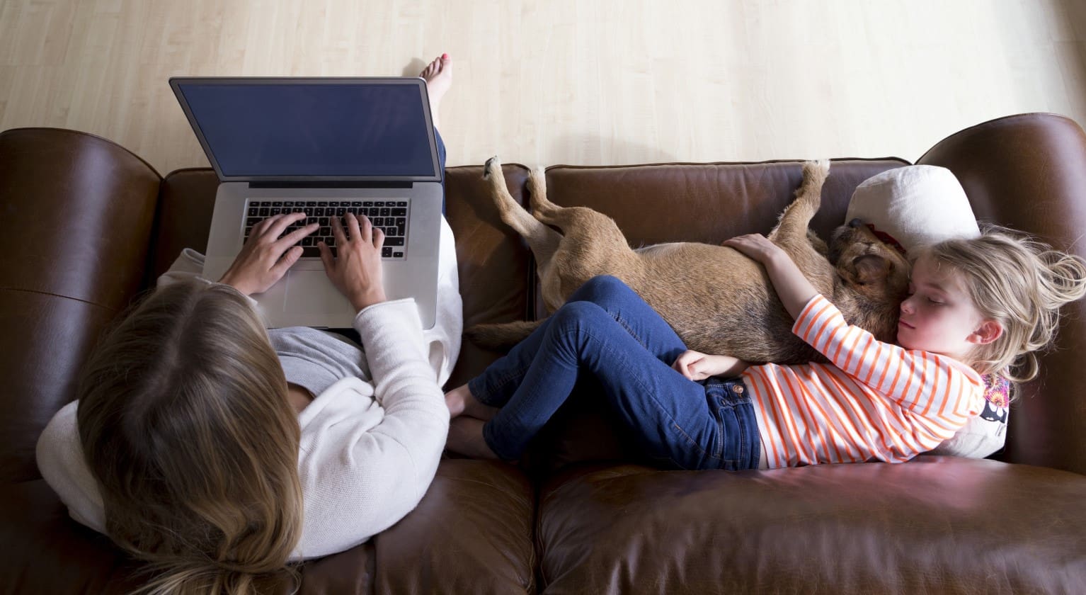 Overhead view of mum, daughter and dog relaxing on their sofa