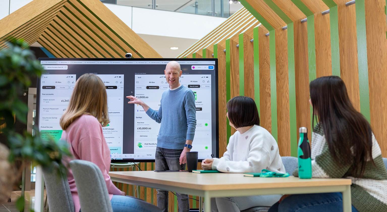 Dan standing presenting to a group of colleagues about the Lloyds Bank app