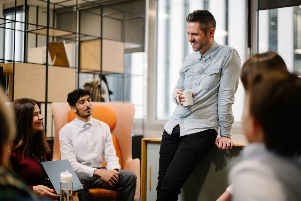 Michael chatting with a group of colleagues in the office
