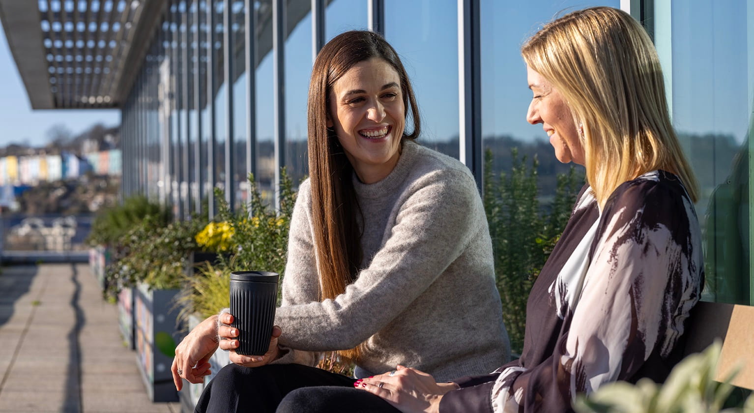 Sally chatting with a colleague on the sunny harbourside balcony in our Bristol office