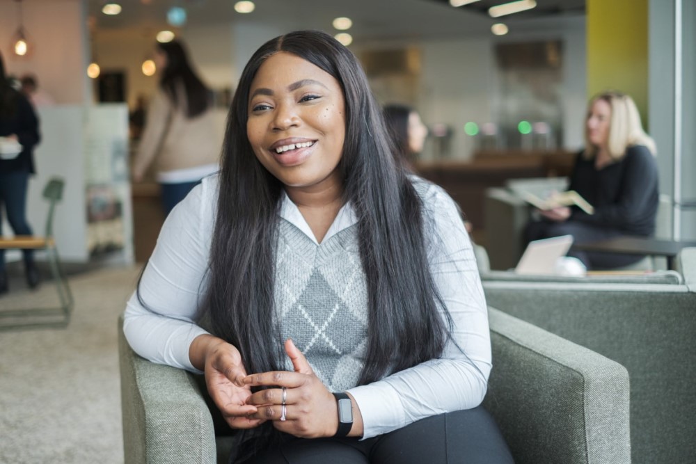 Olufunke sitting in an office talking to someone off-screen and smiling