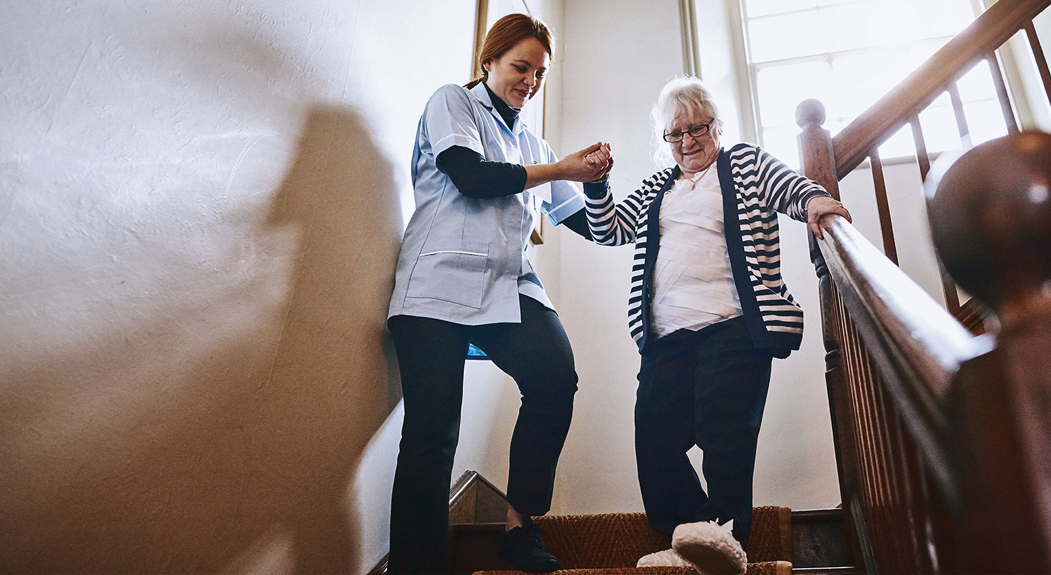 Volunteer helping an elderly woman down the stairs