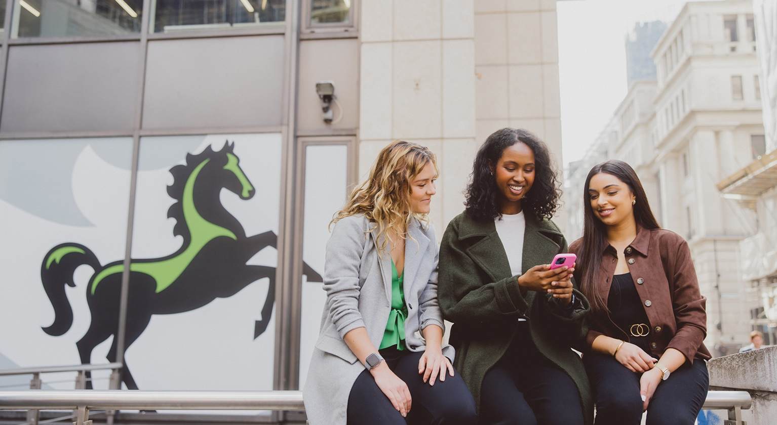 Image showing three girls looking over their phone outside one of our offices