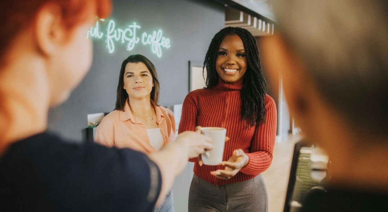 Group of four colleagues holding drinks and smiling