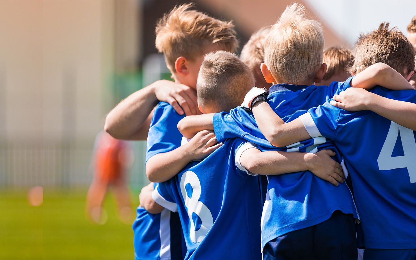 A group of young boys wearing sports kit hugging