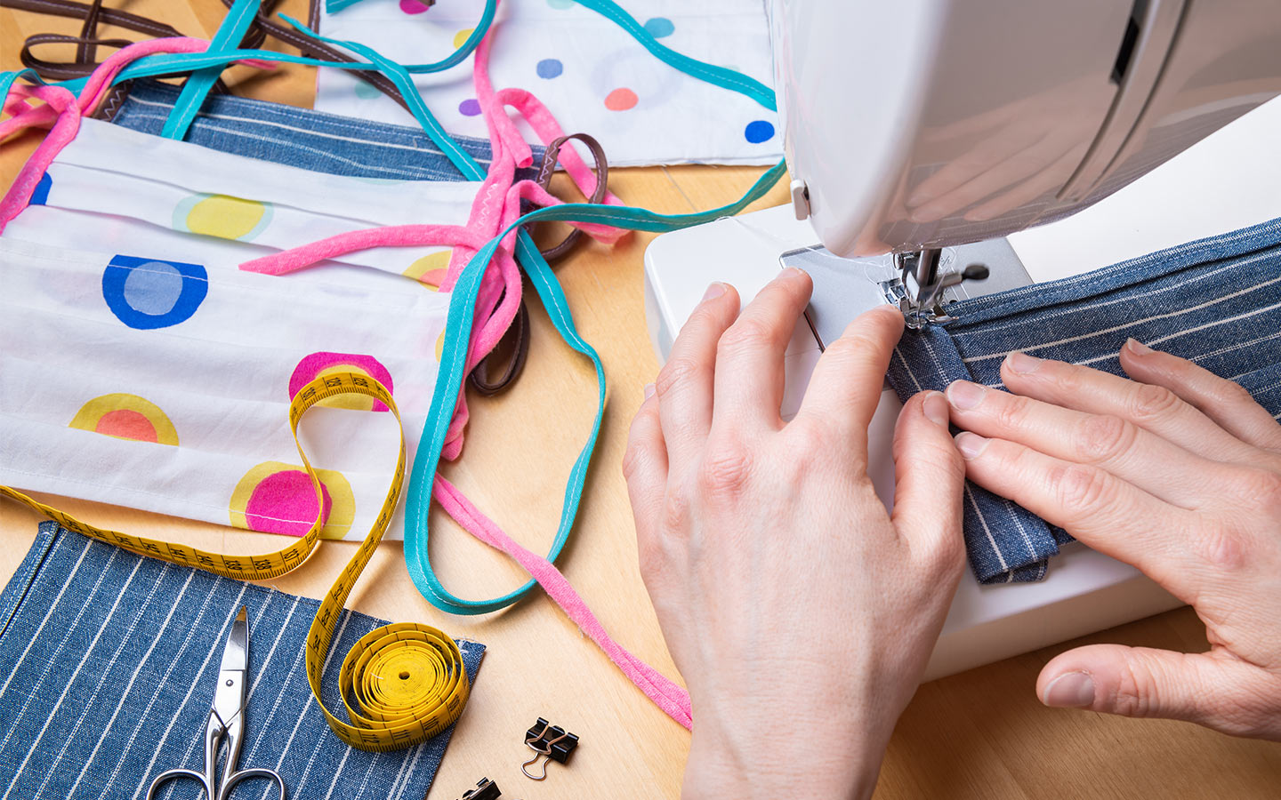 A person using sewing a machine to sew face masks