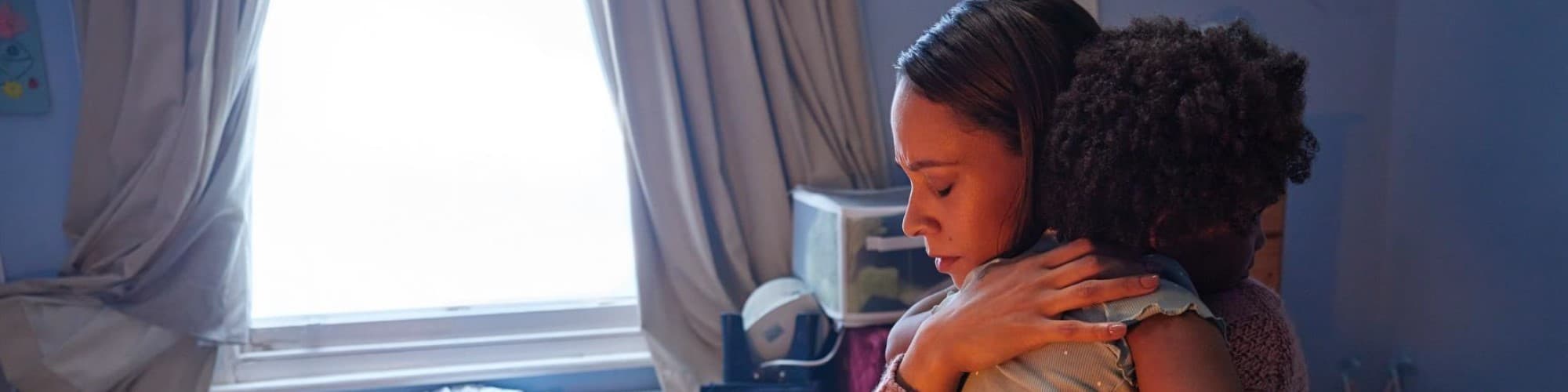 Mother hugs her child, looking sad and anxious 