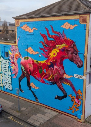 Colourful mural of a flowing red horse painted on a bright blue wall on Grenville Street South, Liverpool, blending Chinese symbols and myth-inspired imagery.
