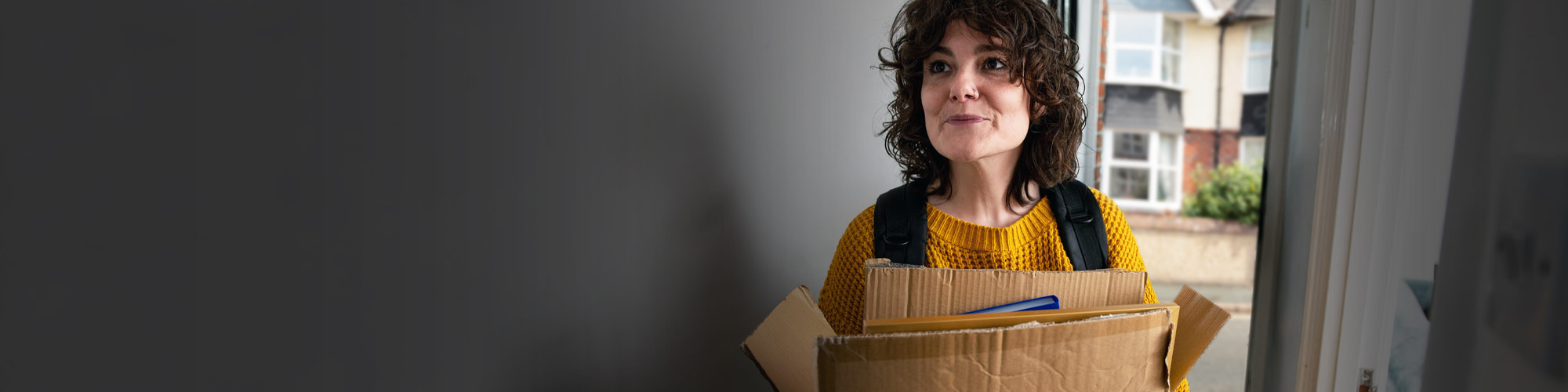 Woman with cardboard boxes in a house doorway